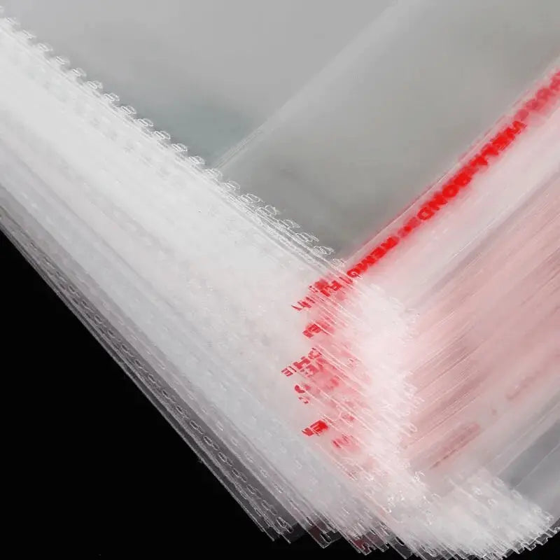Close-up van gestapelde transparante cellofaanzakjes met rode opdruk op de beschermfolie van de plakstrips.